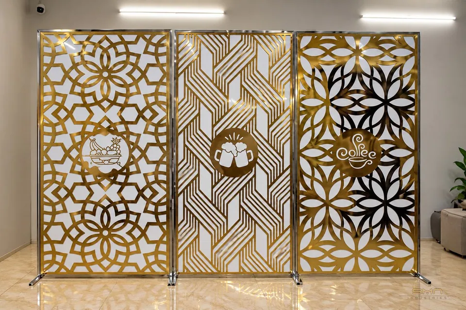 Decorative gold-tone stainless steel partition screens featuring intricate geometric and floral cutout patterns for modern commercial and interior design applications.