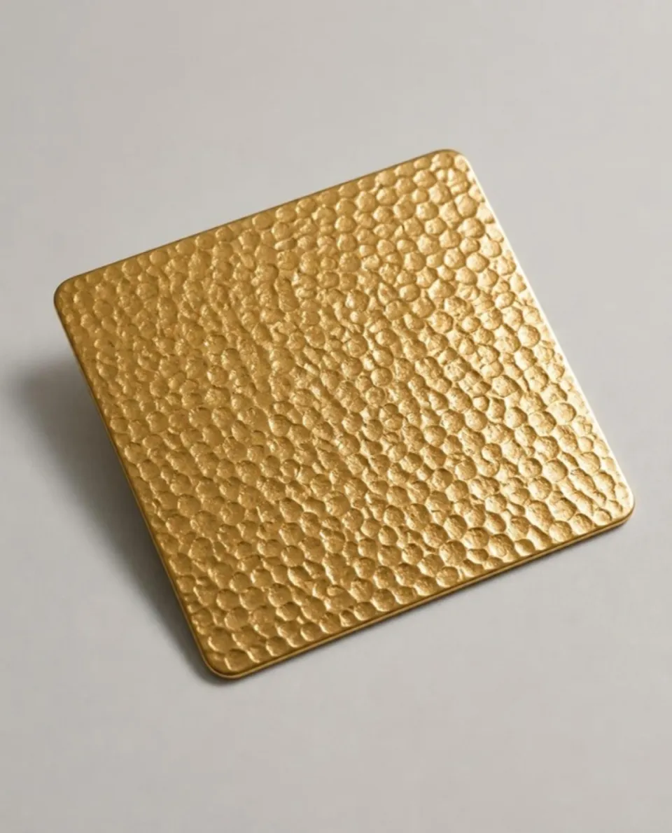 Gold embossed stainless steel sheet sample, raised embossed texture (AI studio visual)